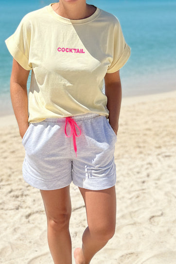  T-shirt jaune femme porté avec short blanc – inscription COCKTAIL rose sur la poitrine, coupe unique 36-42, style estival casual chic
